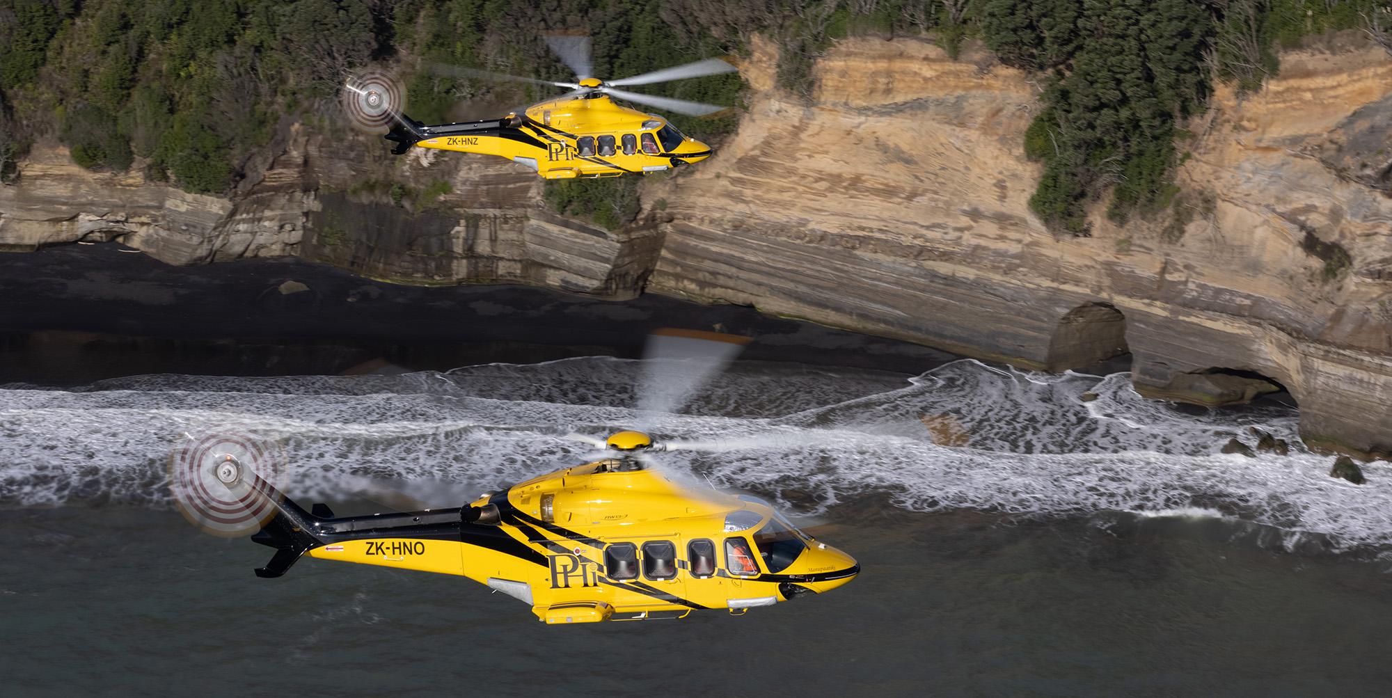 Two PHI helicopters flying over water