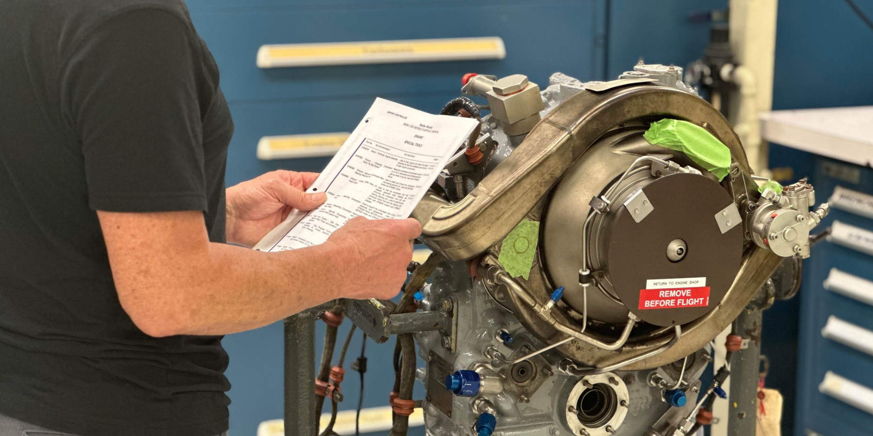 Person looking at paperwork in front of RR engine - Service Bulletin Review - AMC